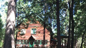 A wooden cabin with a balcony, surrounded by trees.