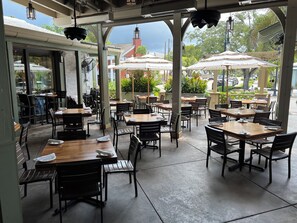 An outdoor cafe with tables and chairs, umbrellas, and a view of the street and buildings. - Great location!!! Old Naples Pool Home - Walk to the beach, shops, restaurants. (Naples)