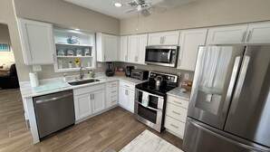 Una cucina moderna con mobili bianchi, elettrodomestici in acciaio inossidabile e pavimento in legno.