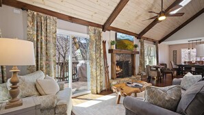 A cozy living room with a fireplace, wooden ceiling beams, and a dining area. - Great Location/100 yd. to lift, Club Member, Walk To Resort & Fire pit!  (Beech Mountain)
