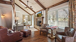 A cozy living room with a fireplace, wooden beams, and a large window with curtains. - Great Location/100 yd. to lift, Club Member, Walk To Resort & Fire pit!  (Beech Mountain)