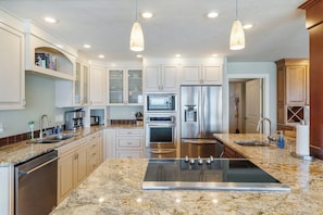 A modern kitchen with granite countertops, stainless steel appliances, and pendant lighting.