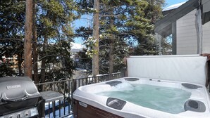 Ein Whirlpool mit Bedienfeld, ein Grill und eine Holzterrasse.