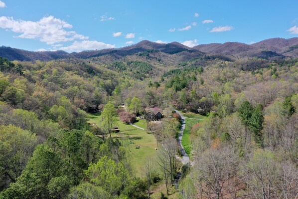 A mountainous landscape with a winding road, dense forest, and a small building with a visible driveway. - Wicklow Woods Studio, Beautiful Mountain views,cool streams and Waterfalls (Andrews)