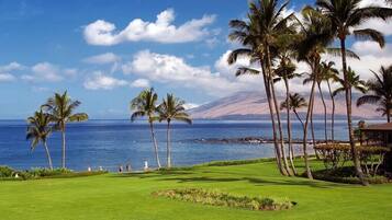 A golf course with a view of the ocean and a mountain in the background.