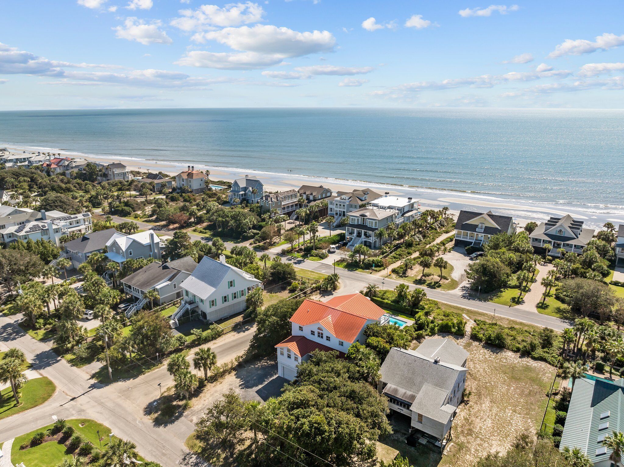 An aerial view of a coastal residential area with houses, roads, and a beach.