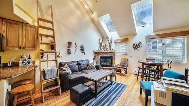 Een gezellige woonkamer met een open haard, een bank, een salontafel en een eethoek met een tafel en stoelen.