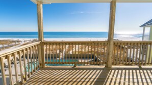 A wooden deck with a view of the beach and ocean.