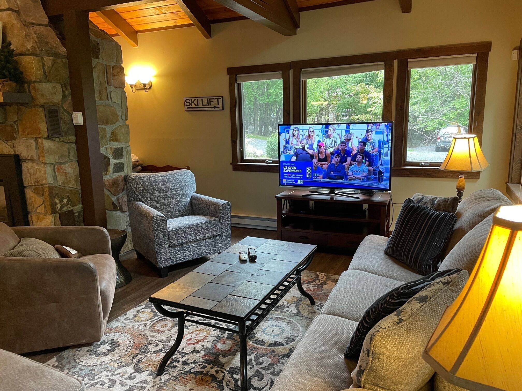 A cozy living room with stone walls, a fireplace, a television, and a comfortable seating area.