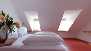 A bedroom with a bed, a nightstand, a vase with flowers, and two skylights. - Hotel Engel Lindauer Bier Und Weinstube (Lindau)