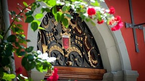 A wrought iron gate with a crest, a red wall, and a white archway. - Hotel Engel Lindauer Bier Und Weinstube (Lindau)