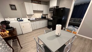 A compact kitchen with white cabinets, a black refrigerator, and a dining area with a table and chairs. - 2BR 1BATH Cozy Cottage Quiet Area! 12mins-Downtown Nashville 10mins-Brentwood! (Nashville)