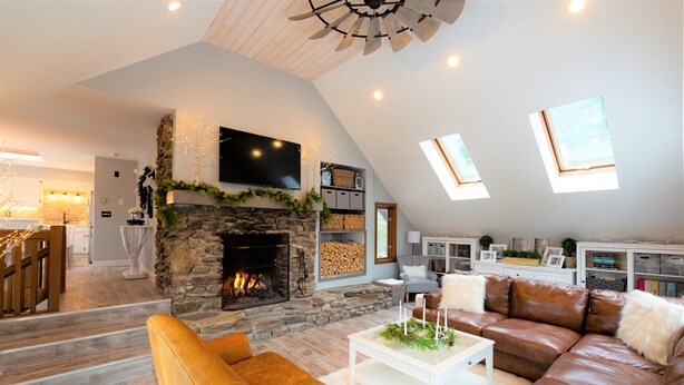 A spacious living room with a stone fireplace, leather sofas, and a television mounted on the wall. - Beautiful Mountain Getaway - Last Minute Booking Promos! Minutes from Manchester (Peru)
