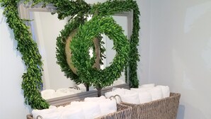 A wooden vanity with two wicker baskets filled with white towels, a mirror with a heart-shaped wreath, and a small shelf below. - Beautiful Mountain Getaway - Last Minute Booking Promos! Minutes from Manchester (Peru)