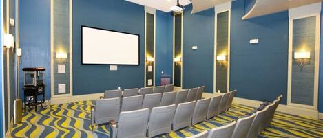 A conference room with rows of chairs, a projector screen, and a patterned carpet.