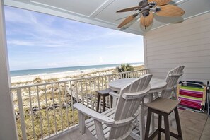 A balcony with a view of the beach, a ceiling fan, and a table with chairs. - SeeRay Shores 202 (St. Augustine)