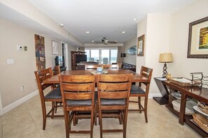 A dining area with a round table and chairs, a ceiling fan, and a view through the window. - SeeRay Shores 202 (St. Augustine)