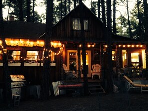 A rustic cabin with a porch, string lights, and a grill area. - Charming Cozy Uniquely Furnished Rustic Cabin Steps to Forest Trails  (Munds Park)
