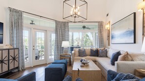 A living room with a sofa, ottomans, a coffee table, and a chandelier. - Blue Haven, Tivoli, Sandestin, Golf Cart (Miramar Beach)
