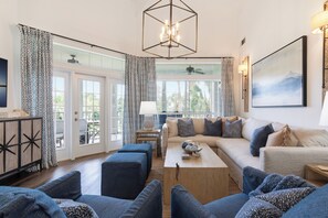 A living room with a sofa, ottomans, a coffee table, and a chandelier.