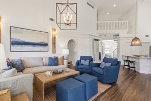 A spacious living room with a sofa, chairs, a coffee table, and a painting on the wall.