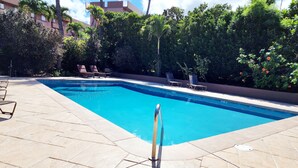 En rektangulär swimmingpool med ett klart, blått vatten och en omgivande poolterrass som är belagd med plattor.