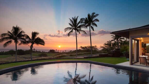 A swimming pool with a sunset view, palm trees, and a building with a glass door. - Ocean Views/Private Swimming Pool. Mauna Kea High Bluffs Home (Mauna Kea Beach Resort)
