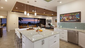 A modern kitchen with a large island, white cabinetry, and a view of the ocean. - Ocean Views/Private Swimming Pool. Mauna Kea High Bluffs Home (Mauna Kea Beach Resort)