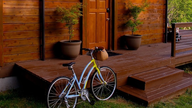 A wooden cabin with a porch, a bicycle, and two potted plants. - ⚓️ Nautical Sea Cabin with Water View ⚓️ (Lopez Island)
