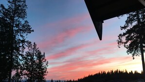 Zonsondergang vanaf een balkon met uitzicht op een woonwijk met huizen en bomen.