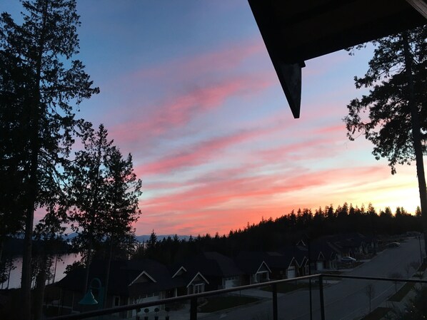 A sunset view from a balcony overlooking a residential area with houses and trees.