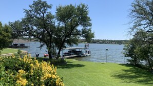 Blick auf einen See mit Steg, Rasenfläche und Bäumen.