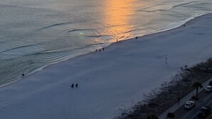 Ein Strand bei Sonnenuntergang, ruhiges Meer und einige Spaziergänger.