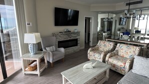 Ein modernes Wohnzimmer mit Fernseher, einer Couch, einem Couchtisch und einem Kamin.
