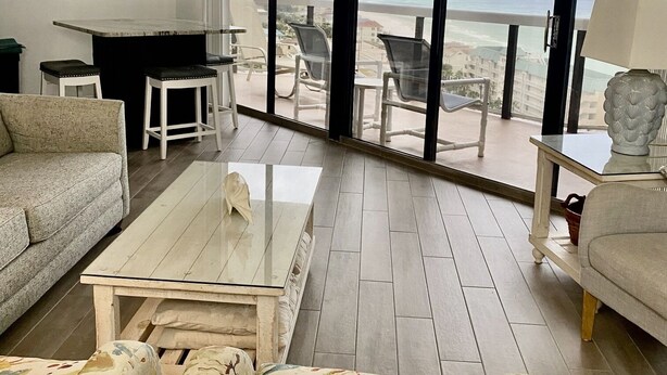 Ein geräumiges Wohnzimmer mit einem großen Glasfenster, das auf einen Balkon mit Meerblick führt.