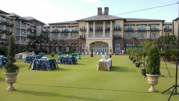 A courtyard with tables and chairs set up for an event, surrounded by a multi-story building with balconies and a central entrance. - Affordable, Comfortable 2 Bed, 2 Bath Villa - walk to beach! (Kiawah Island)