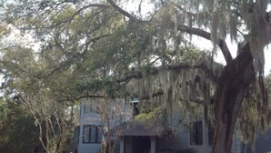 A house with a porch, surrounded by trees and a fence. - Affordable, Comfortable 2 Bed, 2 Bath Villa - walk to beach! (Kiawah Island)