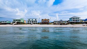 Una propiedad frente a la playa con varias casas conectadas por un muelle, que cuenta con balcones y acceso directo a la playa.