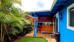 A kitchen with wooden cabinets and a blue exterior wall. - Slice of Heaven Studio (Waialua)