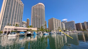 A marina with several boats docked, surrounded by high-rise buildings and palm trees. - Slice of Heaven Studio (Waialua)