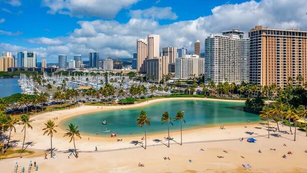 A coastal cityscape with a beach, palm trees, and high-rise buildings. - Slice of Heaven Studio (Waialua)
