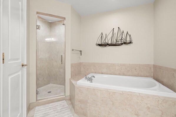 A bathroom with a walk-in shower, a bathtub, and a wall-mounted ship decoration.