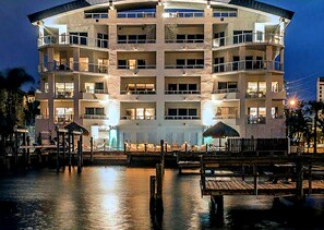 A multi-story hotel with balconies, a pool area, and a waterfront view.