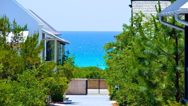 Una propiedad costera con vistas al mar, rodeada de exuberante vegetación y una entrada con portón cerrado.