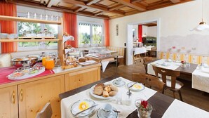 A breakfast buffet with various food items and a dining area with tables set for guests.