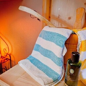 A wooden chair with a striped towel draped over it, a bottle of perfume, and a wooden wall. - Hotel Bergblick (Scheidegg)