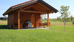 A wooden cabin with a sloped roof, a dining area with benches, and a small kitchen area.