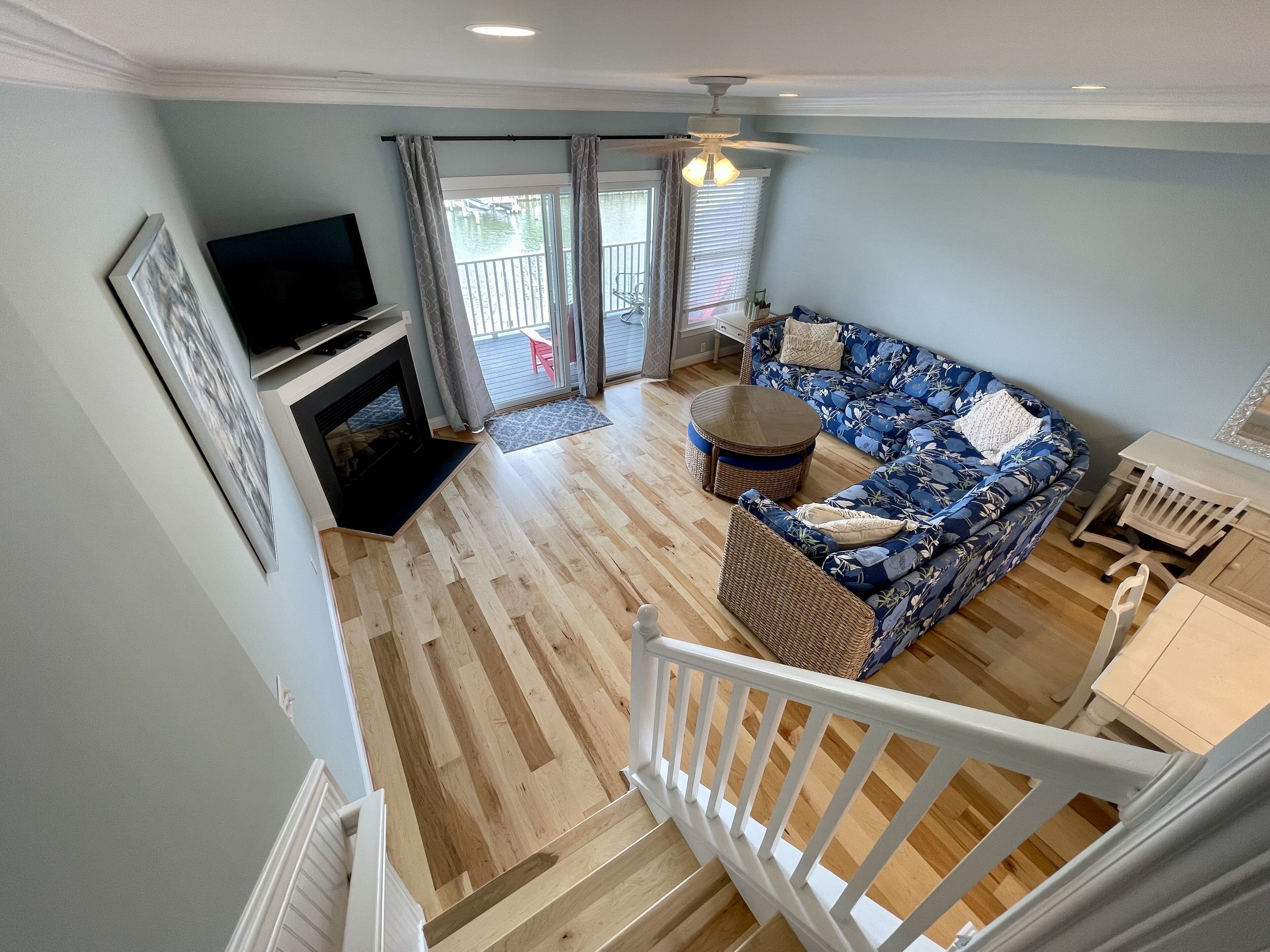 A spacious living room with a fireplace, a large sofa, a round coffee table, and a television.