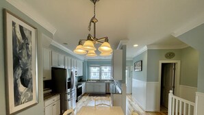 A spacious kitchen with white cabinetry, a large dining table, and pendant lighting.