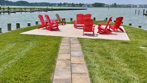 A lakeside deck with red Adirondack chairs and a stone pathway.